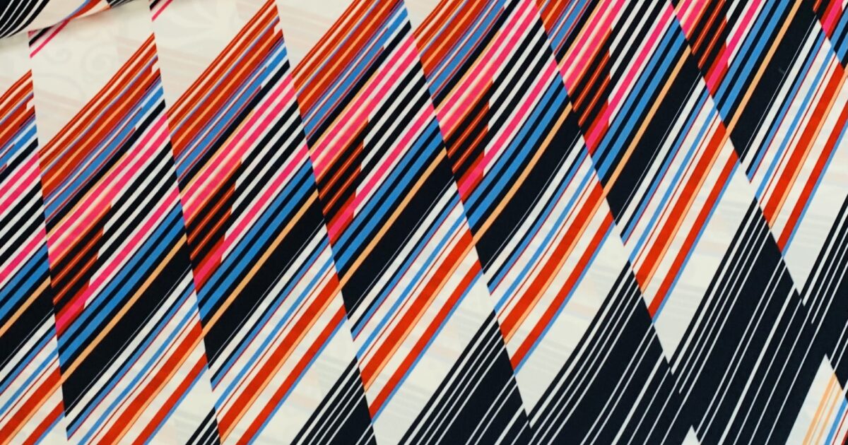 Polyester stretch wit met zwart/blauw/rode schuine… | Megastoffen